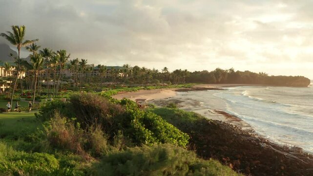 Sunrise in Hawaii at beach. Aerial flight over rolling waves and bay in golden early morning light. Kauai Poipu Shipwrecks
