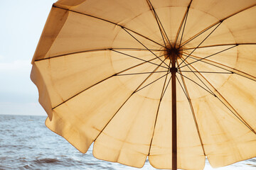 Relaxing on the beach. A yellow beach umbrellas on a sandy beach at sunset.