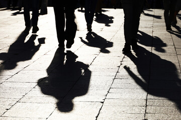 Black silhouettes and shadows of people on the street. Crowd walking down on sidewalk, concept of pedestrians, crime, society, city life