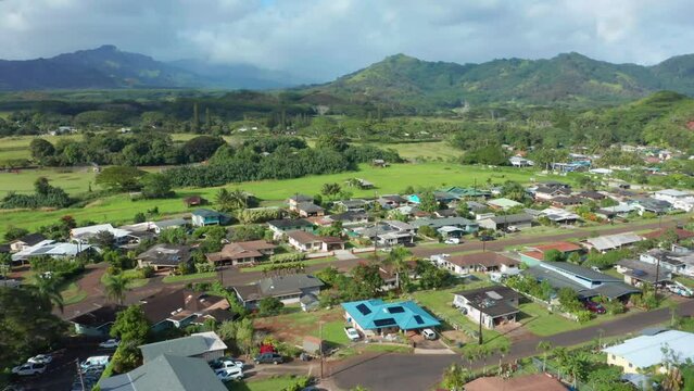 Houses in nature in Kauai Poipu Koloa. Drone Flying Over Beautiful neighbourhood in Hawaii with Mountain Range in Distance. Single family homes from above in green natural environment on sunny day