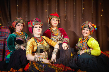 Four women in colorful traditional costumes pose for a photo. A tribal dancer poses for a photo...