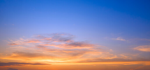 Sunset sky with golden sunlight and orange clouds on horizon blue evening sky background after sundown in panoramic view, Beautiful idyllic natural tranquil scene