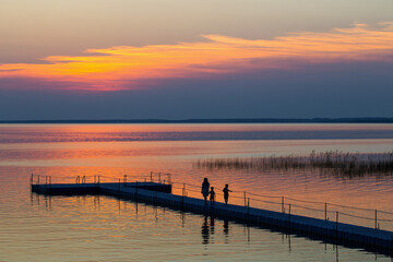 Fototapeta premium family on pontoon pier at sunset