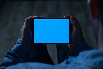 Naklejka premium Device screen seen from a shoulder of a adult man holding an smartphone with a completely blue screen