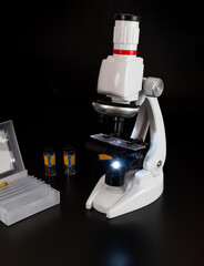 Microscope close-up on a black background table with laboratory objects