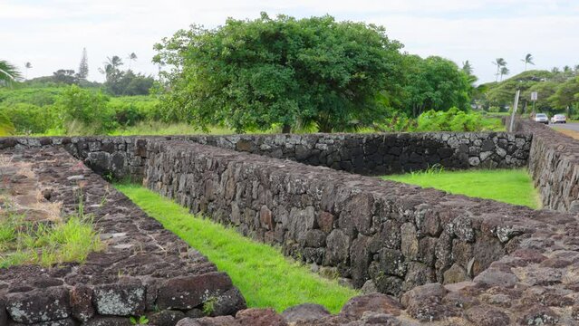 Ancient Hawaiian Village Cultural Site Kaneiolouma. Old Hawaii village located at the corner of Poipu Road Kauai. Walled Heiau temple walls. Cars passing by