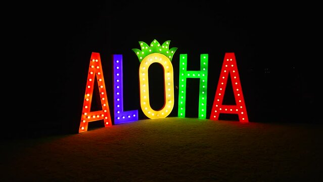 Aloha tall letters in Hawaii. Sign or billboard with illuminated letter at night shining in different colours neon sign. Hawaiian spirit