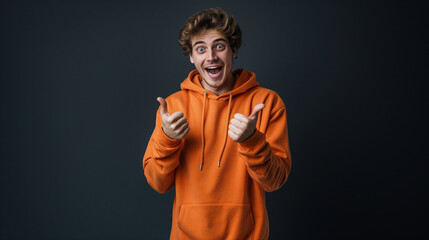 Excited Young Man in Bright Orange Hoodie Giving Thumbs Up with Enthusiastic Expression