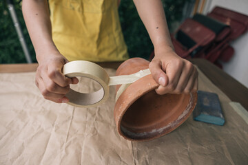 Hands of unrecognizable person preparing a clay pot to paint it