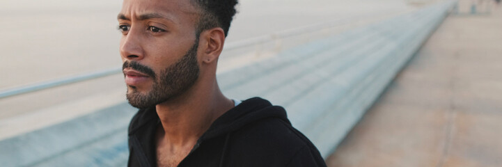 Obraz premium Young bearded male athlete runs along the promenade, panorama