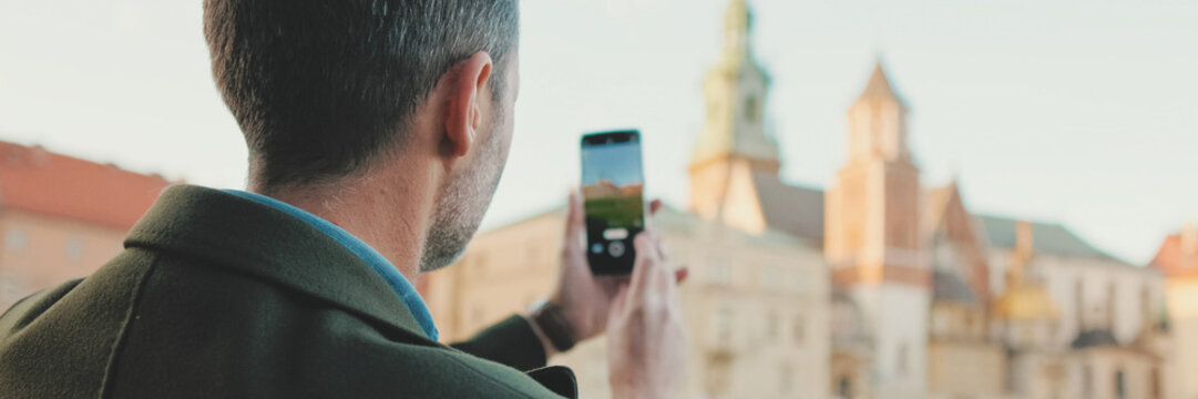 Man takes photo on mobile phone in the old city, Back view, panorama - Powered by Adobe