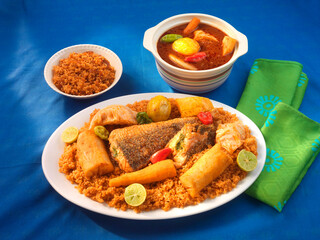 Tiebu Dien, Tiebu Dien auf weissem Teller und blauem Tischtuch mit gruener Serviette. Afrika, afrikanisches Essen, Ghana, Fisch, 