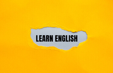 Learn english message written on ripped yellow torn paper with gray background. Conceptual learn...