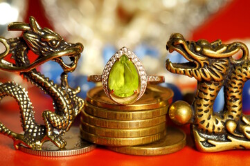 A statuette of a Chinese dragon with coins and a green ring.
