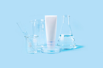 cosmetic tube, Petri dish and laboratory flasks on a blue background