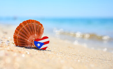 Sandy beach in Puerto Rico. Flag of Puerto Rico in the shape of a heart and a large shell. A wonderful seaside resort. © Nikita