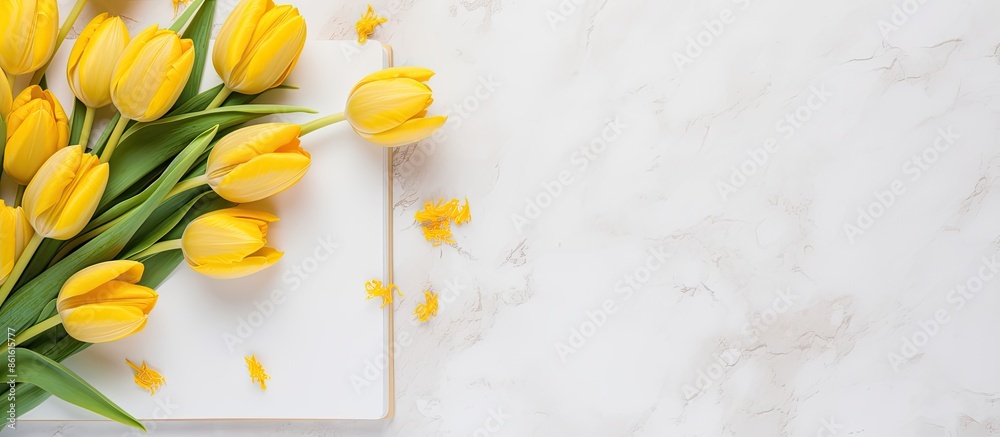 Poster Top view arrangement of fresh yellow tulips on a marble surface with a notepad and sketchbook, providing copy space in a delightful spring-themed image.
