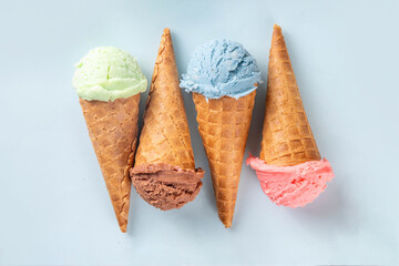 Colorful bright ice cream in waffle cones on bright background. Variety of ice cream cones with different flavor with fresh berries top view copy space layout background