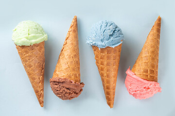 Colorful bright ice cream in waffle cones on bright background. Variety of ice cream cones with different flavor with fresh berries top view copy space layout background