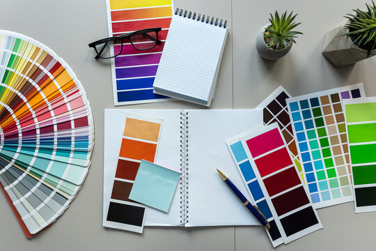 color palette guide for printing with brushes, blank notepad at office desk. Creative workplace