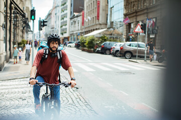 Delivery man with large backpack riding bicycle in urban setting