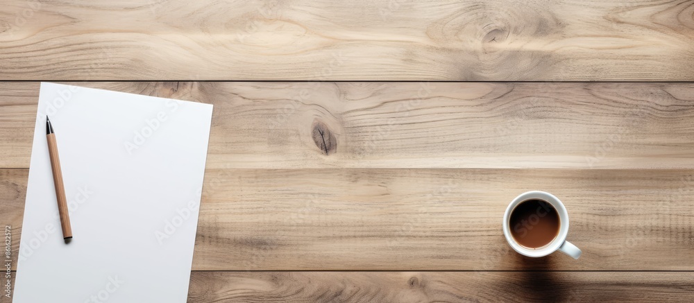 Poster top view of a wood table in an office setting with a blank notepad, a coffee cup, and a pen, providi