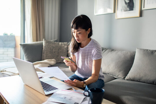 Asian Woman Working from Home with Laptop and Phone
