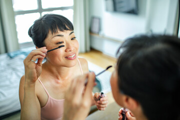 Asian Woman Applying Mascara in Mirror