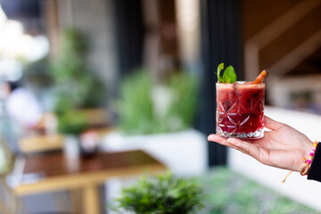 Raspberry cocktail with lime,mint,ice cubes and fresh berries on grey background with juicy summer greenery.