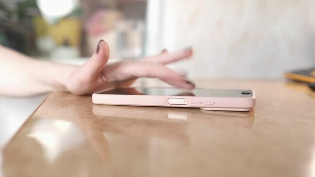 Close up of woman's hand quickly presses her fingers on smartphone screen, earning virtual crypto coins. Taping for online earning of tokens. Crypto app 