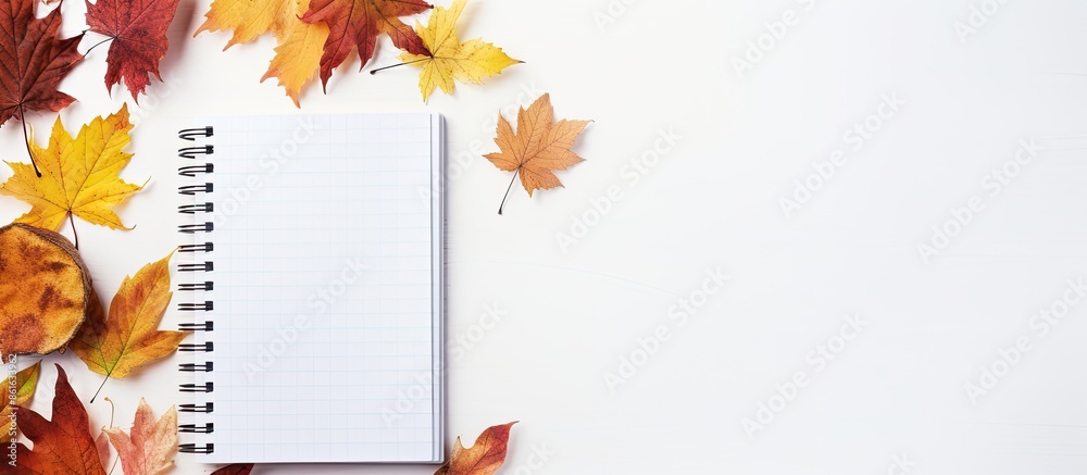 Aufkleber an autumn-themed composition featuring a notebook surrounded by colorful autumn leaves against a lig