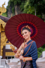 Woman wearing Thai dress visits beautiful temple in Thailand.