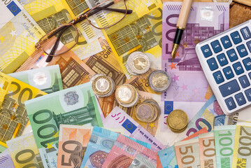 Euro paper money banknotes with metal coin and calculator as finance background.