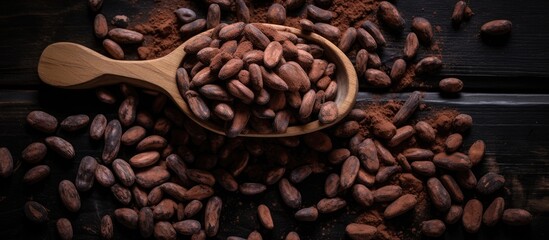 Raw unpeeled cocoa beans are arranged in a pile on a wooden surface against a black backdrop, with a top-down view highlighting an area for additional text or images. Ideal for illustrating the