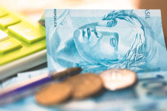 Real - Brasil. Notas de 100 reais sobre a mesa e moedas. Pagamento de impostos e contabilidade. Imposto de renda, irpf, fgts e inss.