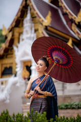 Woman wearing Thai dress visits beautiful temple in Thailand.