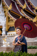 Woman wearing Thai dress visits beautiful temple in Thailand.