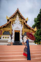 Naklejka premium Woman wearing Thai dress visits beautiful temple in Thailand.