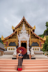 Naklejka premium Woman wearing Thai dress visits beautiful temple in Thailand.