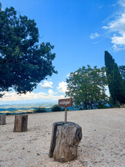 A gravel area with a sign displaying the letter a, surrounded by clouds, sky, buildings, plants, trees, grass, creating a serene natural landscape perfect for city recreation