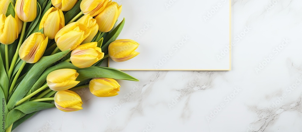 Poster Top view arrangement of fresh yellow tulips on a marble surface with a notepad and sketchbook, providing copy space in a delightful spring-themed image.