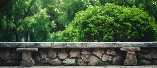 Fototapeta premium Stone park bench with green bushes in the background, perfect for a copy space image.