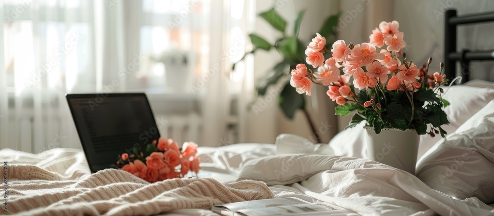 Poster begonia flowers, laptop and magazine on table near bed in light room. with copy space image. place f