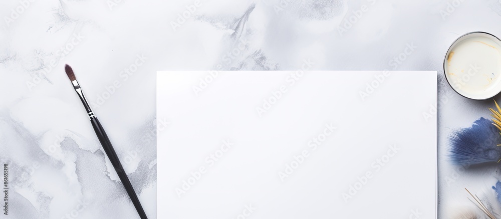 Poster a watercolor set, paintbrush, and sketchbook on a white marble backdrop with a blank area for adding