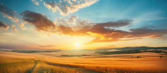 A picturesque sunset scene in summer with a sky filled with lovely clouds above gently sloping hills and a stubble field, perfect for a copy space image.