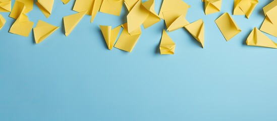 Fototapeta premium Fill half of the frame with a diagonal pattern of yellow paper origami question marks against a pale blue backdrop, leaving room for a copy space image.