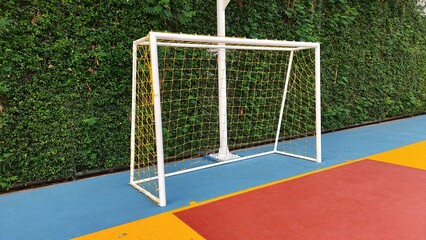 futsal goal with colorful field and green plant wall background