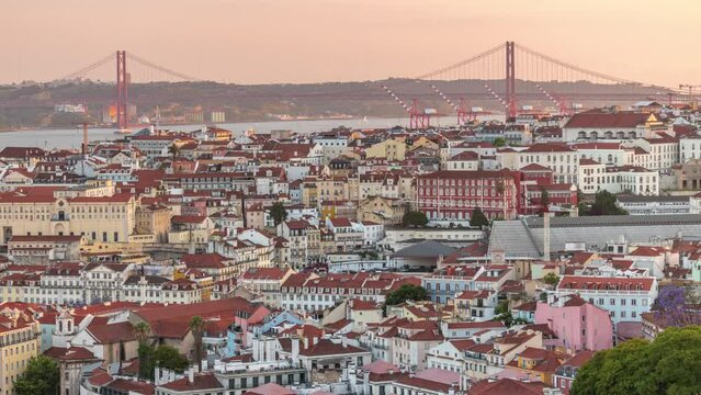 Tagus River and Bridge April 25 or Ponte 25 de Abril aerial timelapse above Orange Roofs of houses in Lisbon, Portugal. Panoramic view from viewpoint Miradouro da Senhora do Monte during sunset
