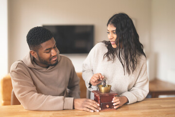Woman Grinds Coffee Beans in Vintage Grinder While Man Watches