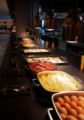 A buffet with a variety of food including eggs, bacon, and toast